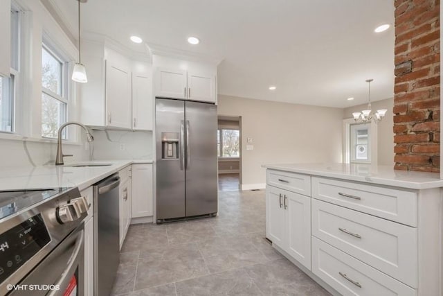 kitchen with sink, white cabinetry, light stone counters, pendant lighting, and stainless steel appliances