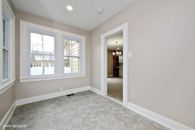 spare room with a notable chandelier