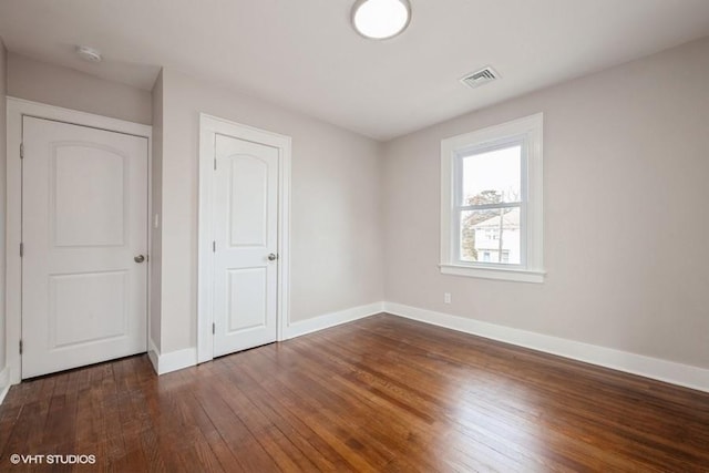 unfurnished bedroom with dark hardwood / wood-style floors and a closet