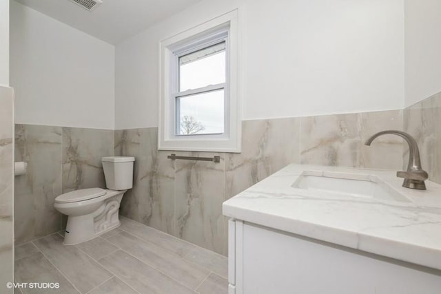 bathroom with vanity, tile walls, and toilet