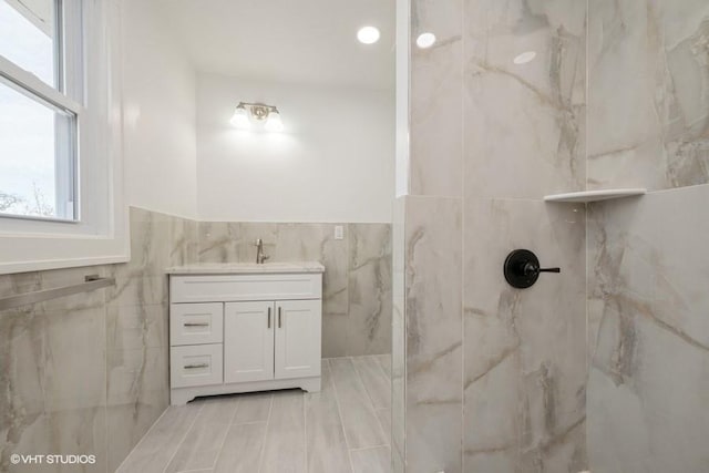 bathroom with walk in shower, vanity, and tile walls