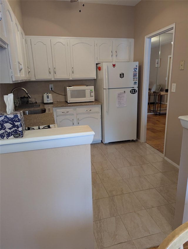 kitchen with white cabinetry, sink, and white appliances