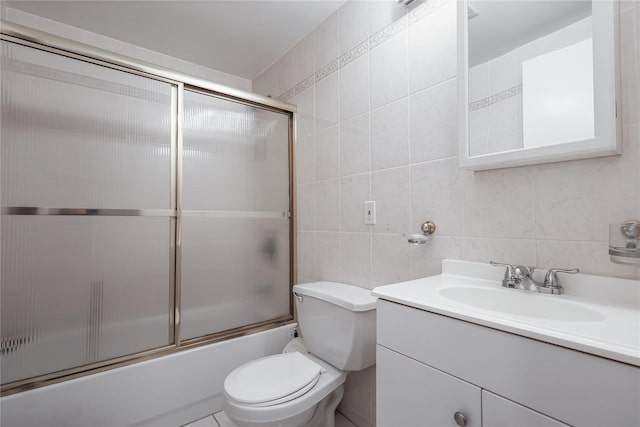 bathroom with combined bath / shower with glass door, toilet, tile walls, and vanity