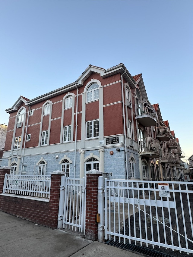 view of front of property with brick siding, a fenced front yard, and a gate