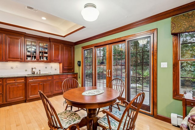 dining area with french doors, sink, crown molding, light wood-type flooring, and a baseboard radiator