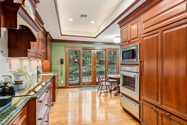 kitchen with sink, appliances with stainless steel finishes, backsplash, light hardwood / wood-style floors, and a raised ceiling