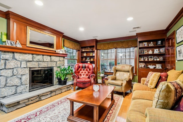 living room featuring baseboard heating, ornamental molding, a fireplace, and light hardwood / wood-style flooring