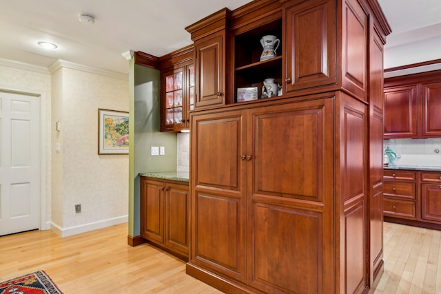 kitchen with tasteful backsplash, crown molding, light stone countertops, and light wood-type flooring