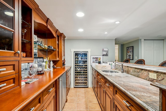 bar with sink, wine cooler, light stone counters, ornamental molding, and light tile patterned flooring