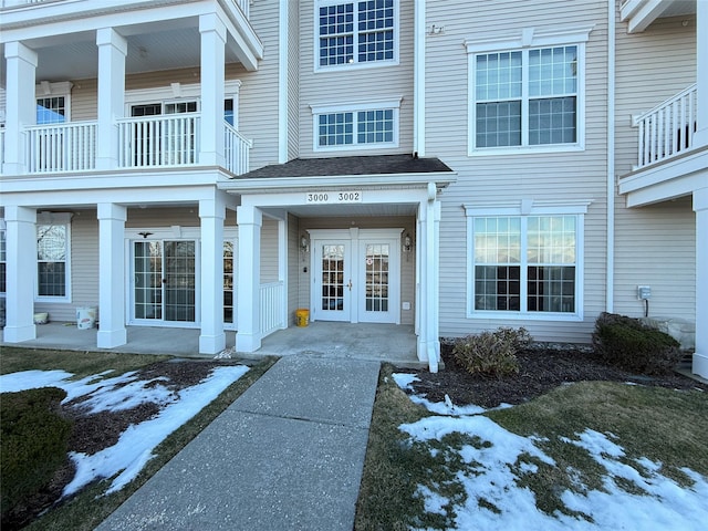 snow covered property entrance featuring french doors