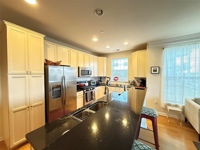 kitchen featuring stainless steel appliances, sink, dark stone countertops, and light wood-type flooring