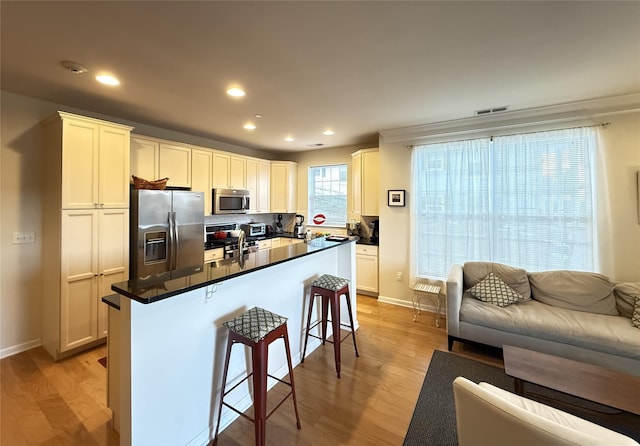 kitchen featuring white cabinetry, stainless steel appliances, light hardwood / wood-style floors, and a breakfast bar area