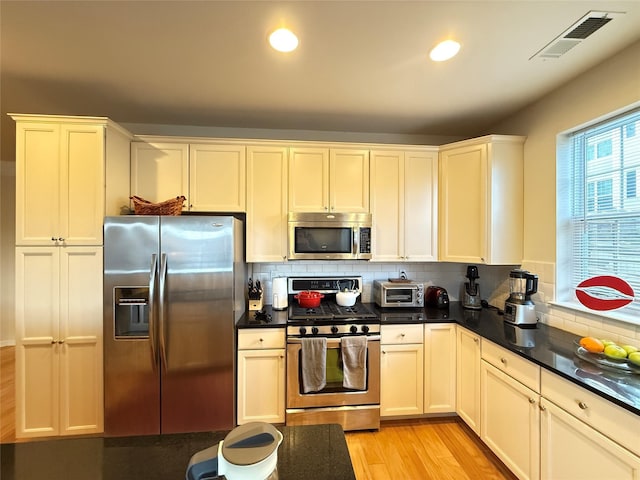 kitchen with stainless steel appliances, tasteful backsplash, and light wood-type flooring