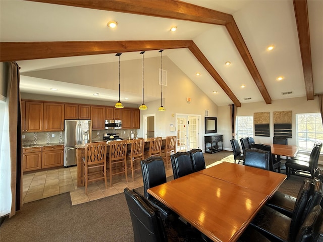 carpeted dining room with beamed ceiling and high vaulted ceiling