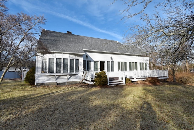 rear view of house with a yard, a deck, and a sunroom