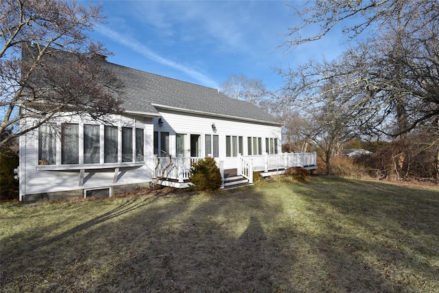 rear view of property featuring a wooden deck and a lawn