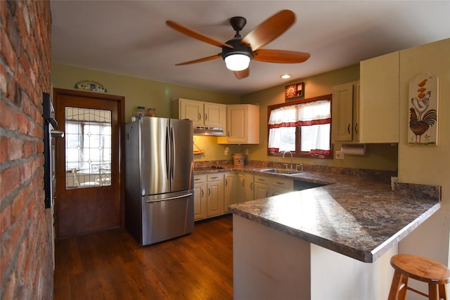 kitchen with a breakfast bar, sink, stainless steel refrigerator, dark hardwood / wood-style flooring, and kitchen peninsula