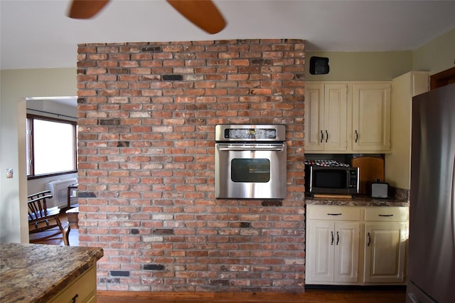 kitchen featuring cream cabinets, stainless steel appliances, and dark stone counters