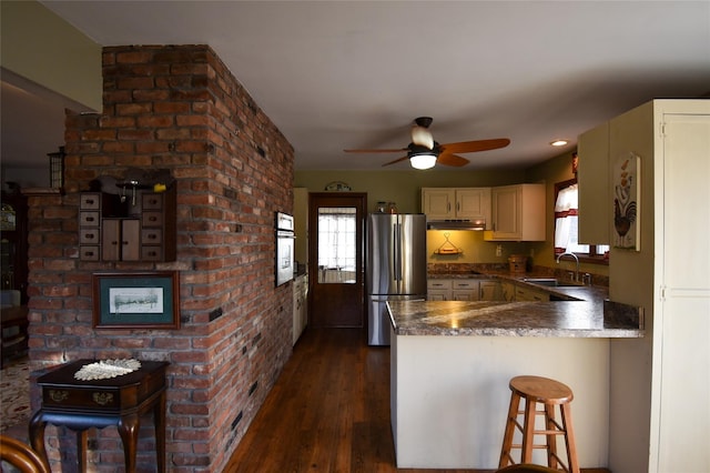 kitchen featuring sink, a kitchen bar, kitchen peninsula, stainless steel appliances, and a healthy amount of sunlight