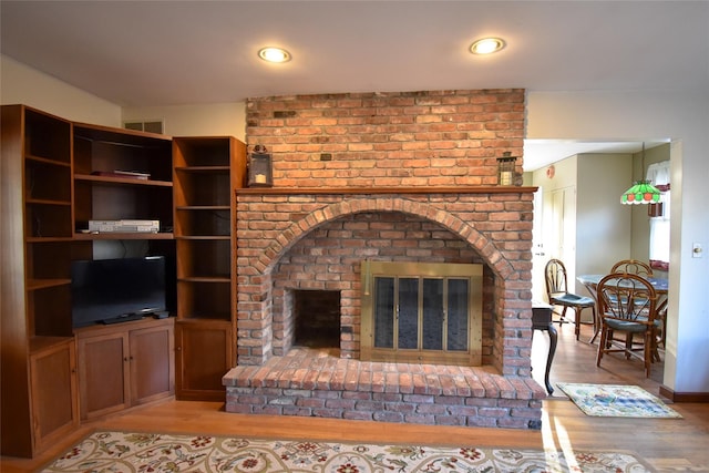 living room featuring a brick fireplace and light hardwood / wood-style flooring