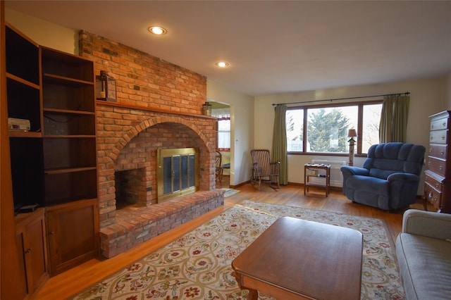 living room featuring a brick fireplace and light hardwood / wood-style flooring