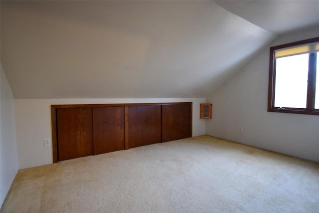 bonus room with vaulted ceiling and light colored carpet