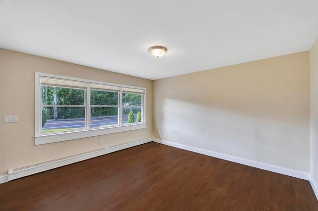 spare room with a baseboard heating unit and dark wood-type flooring