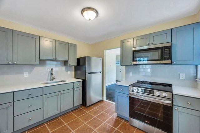 kitchen featuring tasteful backsplash, sink, stainless steel appliances, and dark tile patterned flooring