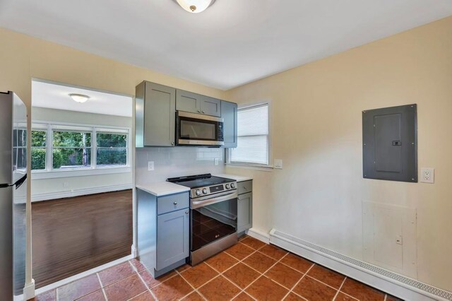 kitchen with tasteful backsplash, a baseboard radiator, appliances with stainless steel finishes, electric panel, and dark tile patterned floors