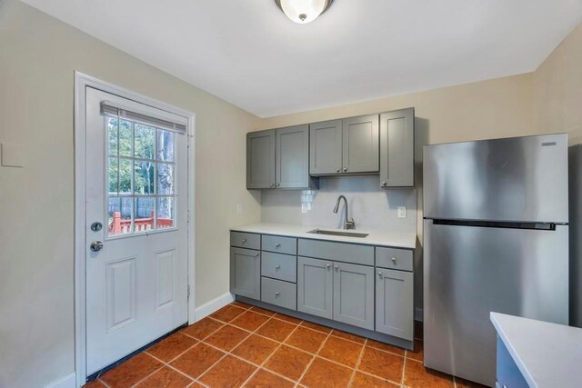 kitchen featuring gray cabinets, sink, stainless steel fridge, and dark tile patterned flooring