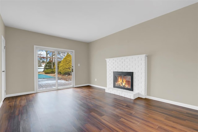 unfurnished living room featuring dark hardwood / wood-style flooring and a brick fireplace