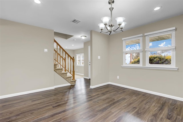 empty room with dark hardwood / wood-style flooring and a chandelier