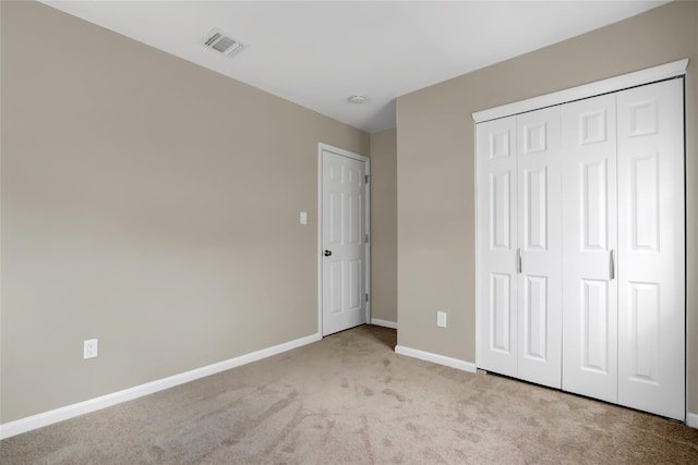 unfurnished bedroom featuring light colored carpet and a closet