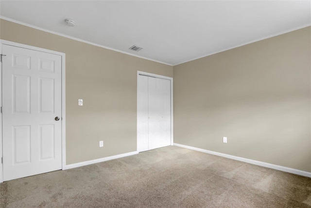 unfurnished bedroom with crown molding, carpet, and a closet