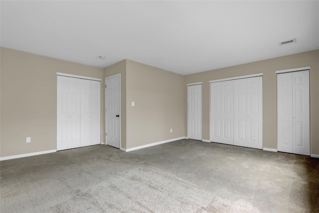 unfurnished bedroom with carpet floors and two closets