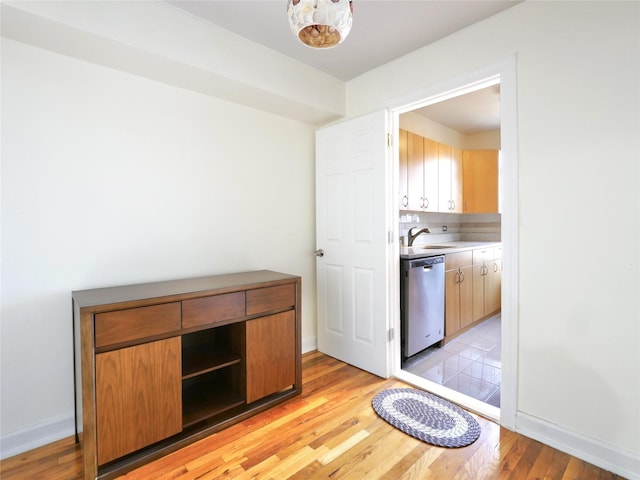 kitchen featuring dishwasher, sink, backsplash, and light hardwood / wood-style flooring