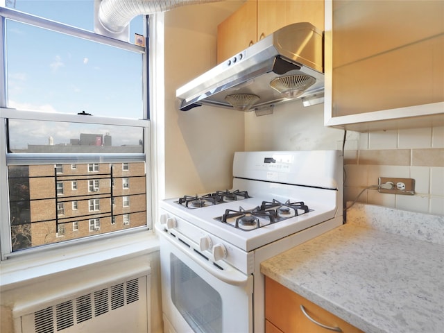 kitchen with radiator heating unit, light stone countertops, and white range with gas stovetop