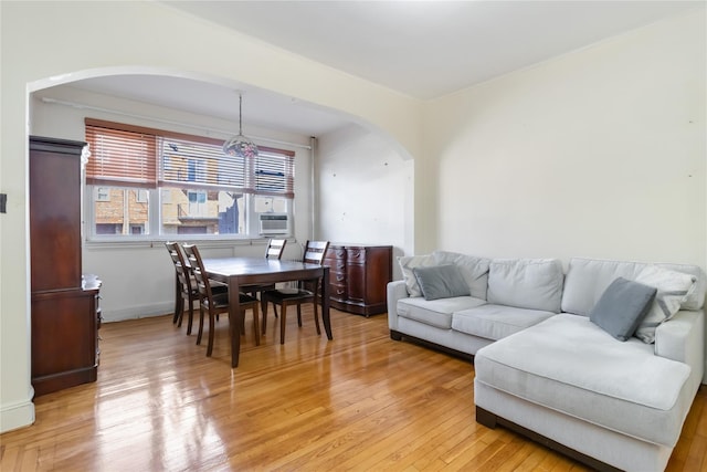 living area featuring arched walkways and light wood finished floors