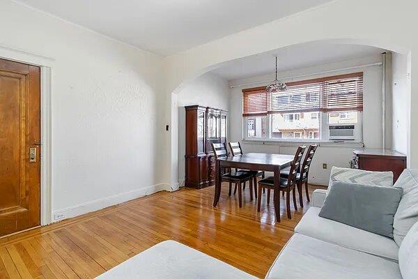 dining area with light wood-style floors, baseboards, and arched walkways