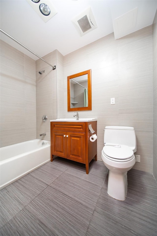 full bathroom with tiled shower / bath, tile walls, tile patterned flooring, vanity, and toilet