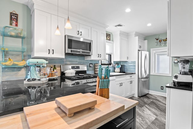 kitchen with sink, white cabinetry, hanging light fixtures, stainless steel appliances, and tasteful backsplash