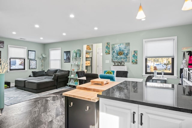 kitchen with white cabinetry, butcher block countertops, decorative light fixtures, and a healthy amount of sunlight