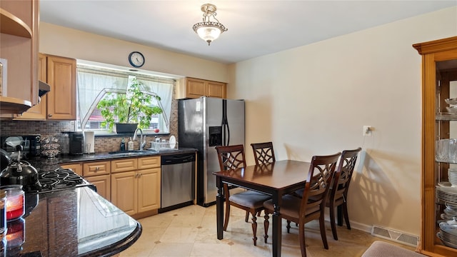 kitchen featuring stainless steel appliances, sink, decorative backsplash, and dark stone counters