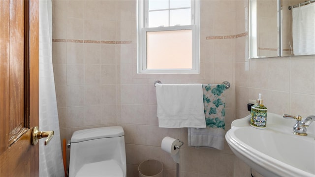 bathroom featuring tile walls, sink, and toilet