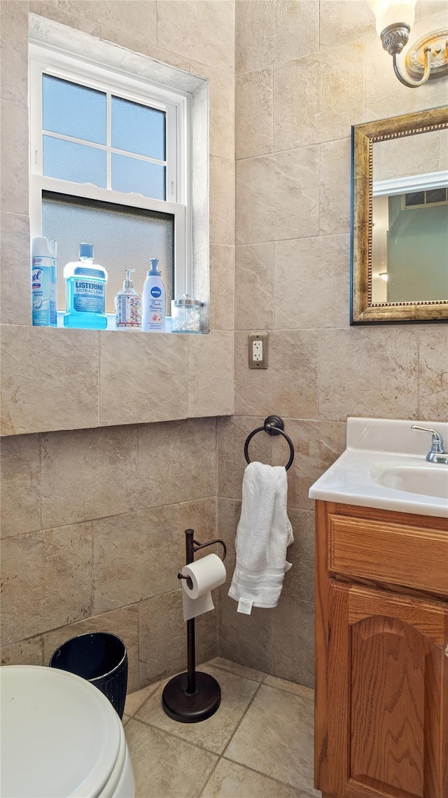 bathroom with tile patterned flooring, vanity, tile walls, and toilet