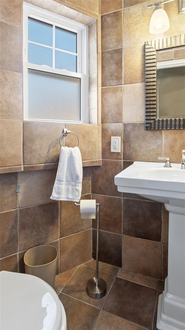 bathroom with toilet and tile walls