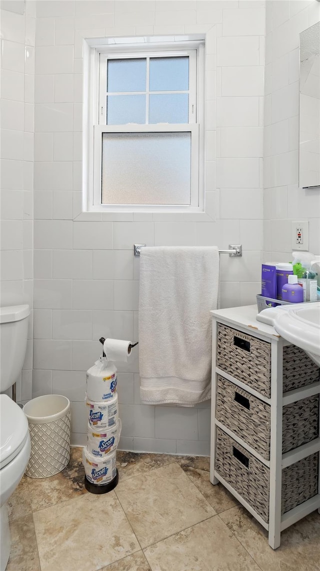 bathroom featuring tile walls and toilet