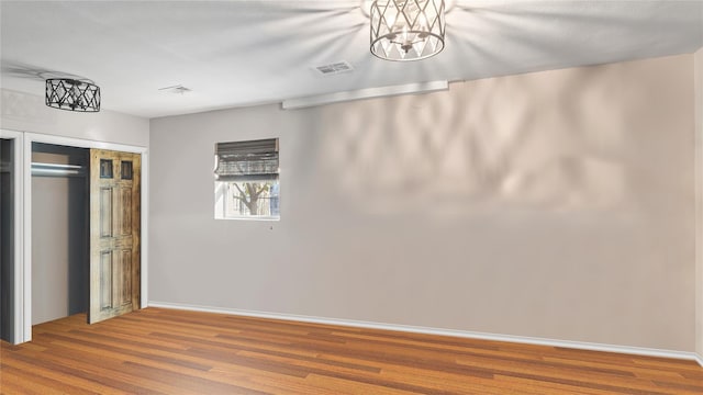 unfurnished bedroom with hardwood / wood-style floors, a closet, and a notable chandelier