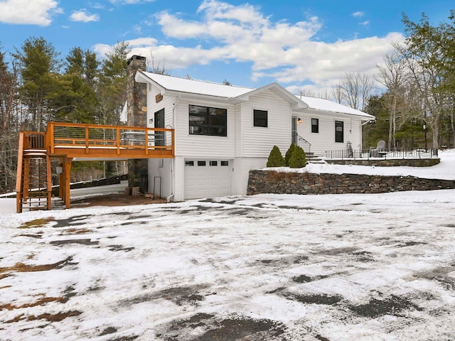 view of snowy exterior featuring a garage and a deck