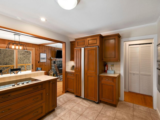 kitchen with pendant lighting, black electric stovetop, tile counters, light tile patterned flooring, and decorative backsplash